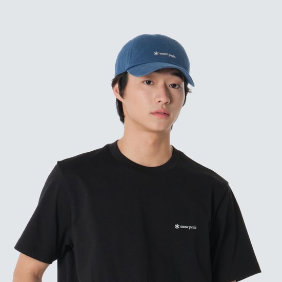 톤 다운된 블루 코튼 볼캡. 전면 중앙에 작은 화이트 별 심볼과 워드마크 자수가 나란히 들어가고 챙은 완만하게 휘어진 형태