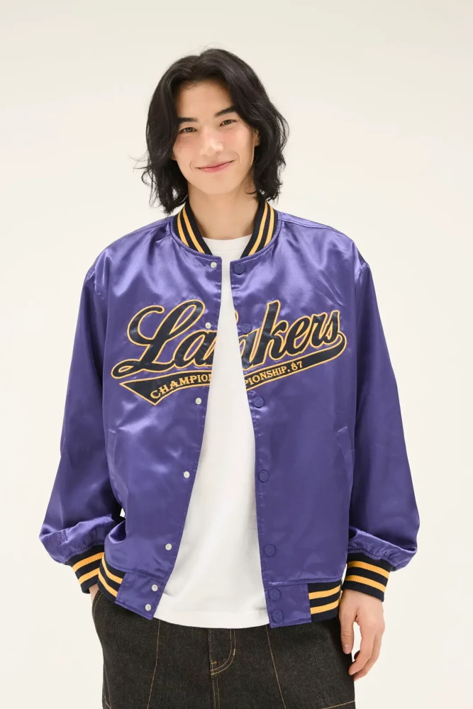 퍼플 새틴 스냅 바시티 점퍼. 가슴에 골드 테두리 Lakers 필기체 레터링과 CHAMPIONSHIP 리본 자수, 옐로·블랙 줄무늬 골지 칼라·소매단·밑단