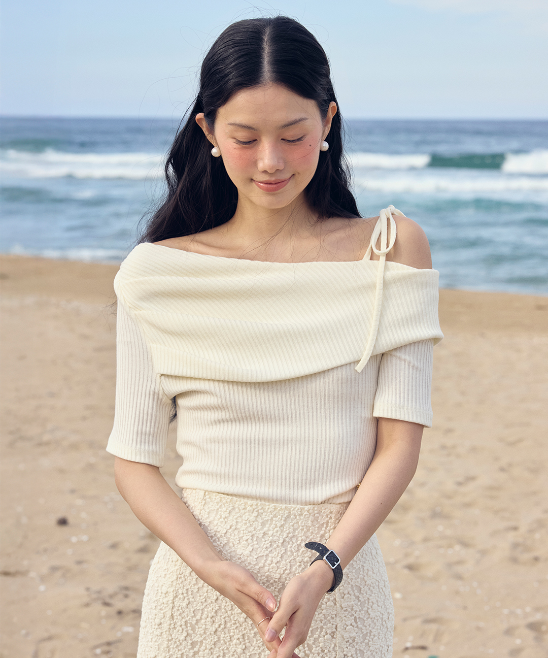 어깨를 드러낸 반팔 니트 톱. 넓은 오프숄더 넥라인에 몸에 붙는 골지 조직