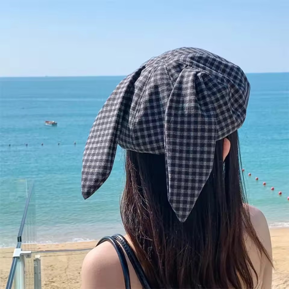 주방에서 신메뉴를 맛보는 장면에 쓴 체크 베레모. 잔잔한 깅엄 체크 원단으로, 정수리에 주름을 잡아 모은 무형태 크라운에 양옆으로 길게 늘어지는 토끼 귀 두 짝이 달려 있고 귀 끝은 뾰족하게 마감됐다. 귀 길이가 턱선 아래까지 내려온다