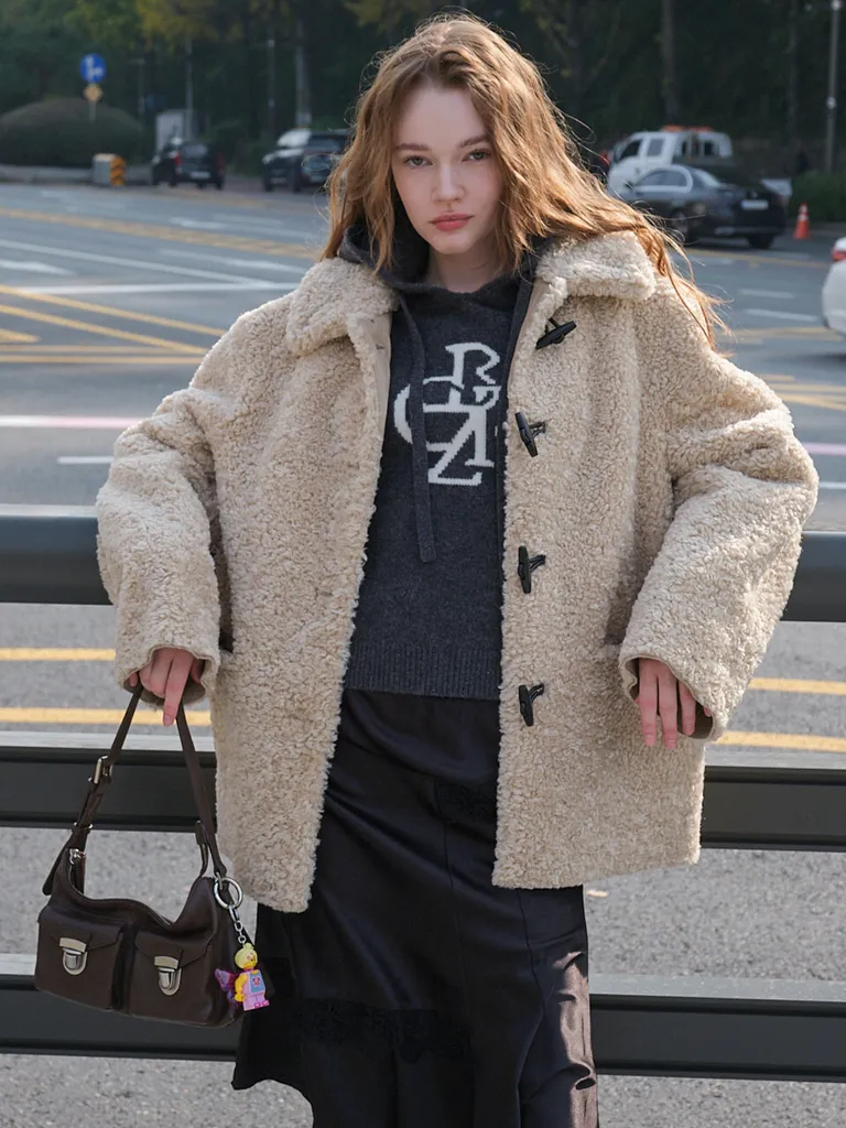 베이지 부클 퍼 숏 더플 점퍼. 칼라가 있고 블랙 토글 단추로 여미며 앞 포켓이 두 개다.