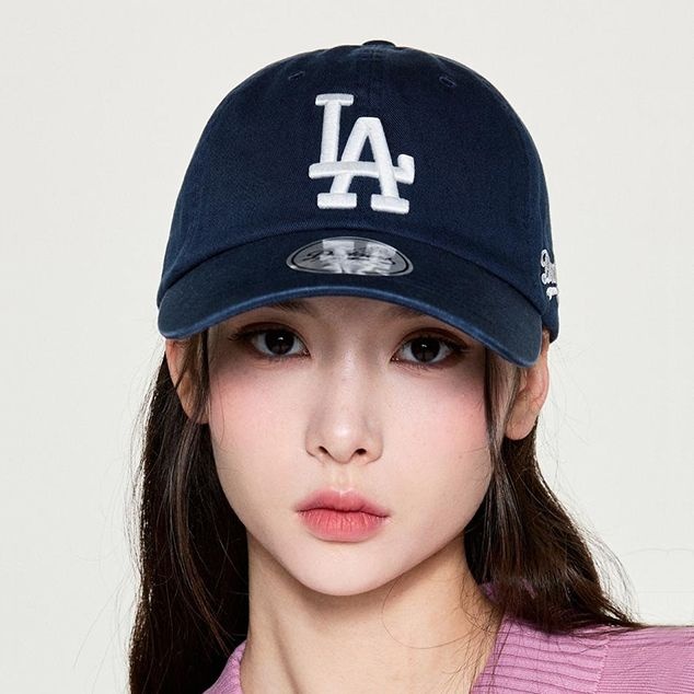 네이비 면 소재의 비구조 볼캡. 앞면에 화이트 입체 자수 LA 로고, 왼쪽 옆면에 화이트 필기체 Dodgers 자수, 챙은 살짝 굽은 형태
