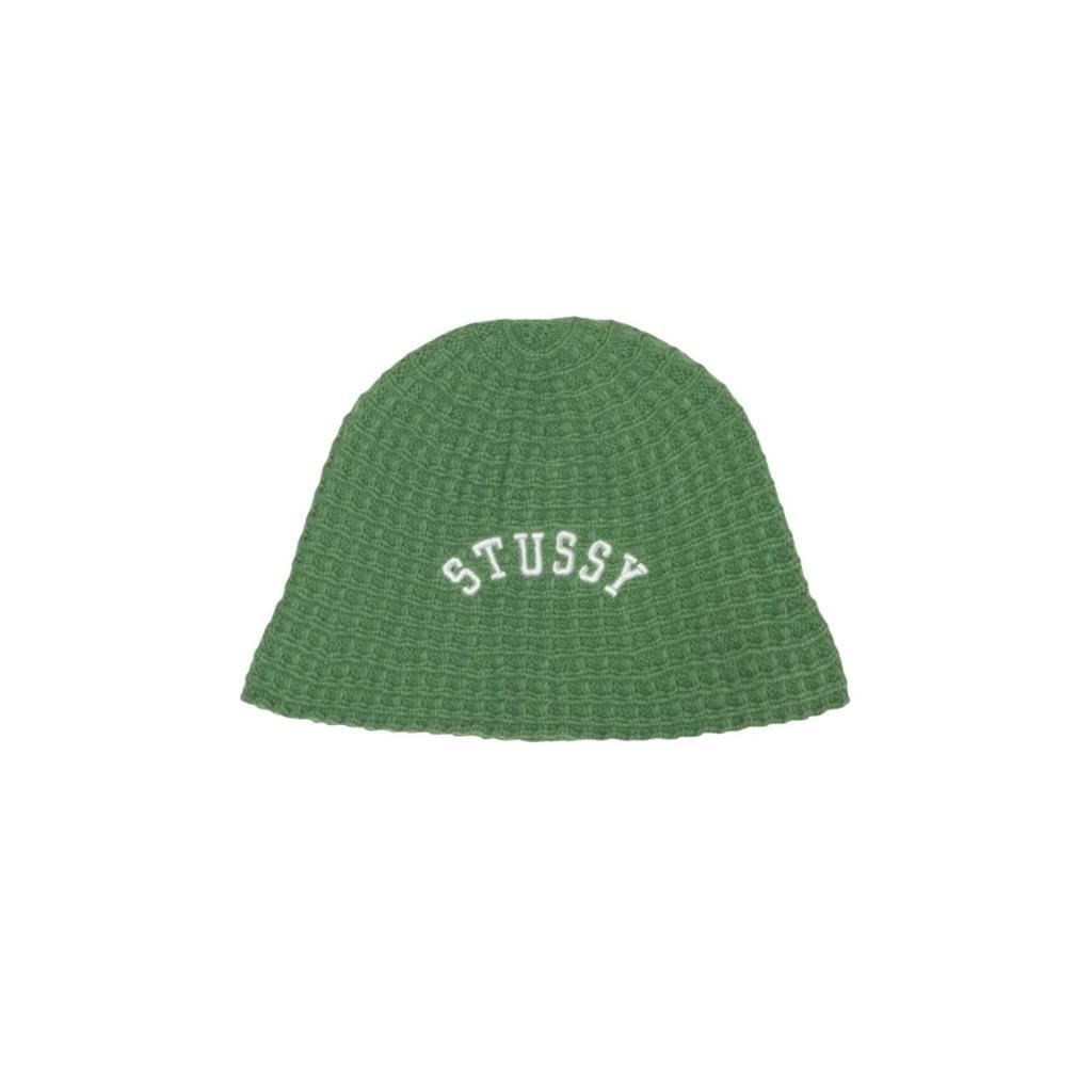 그린 와플 조직 니트로 짠 버킷햇. 앞면 중앙에 화이트 아치형 STUSSY 레터링 자수, 챙이 짧고 부드럽게 늘어지는 형태