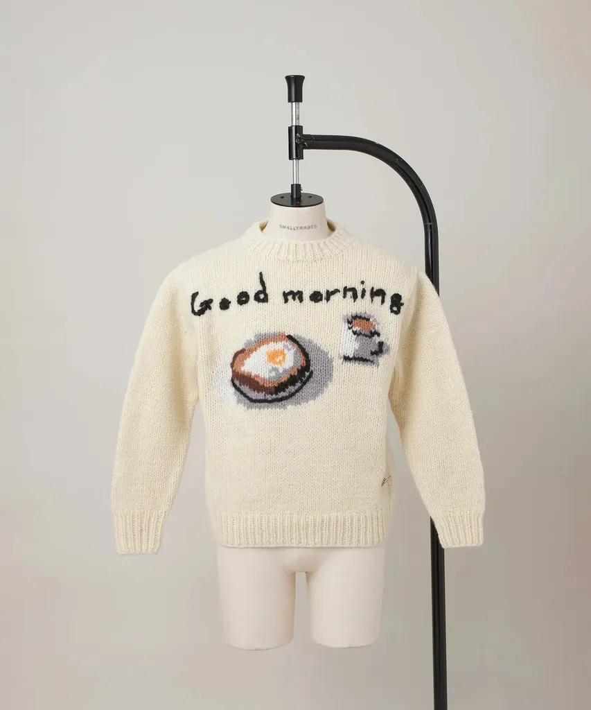 스튜디오 토크 내내 입은 에크루 울 니트. 가슴에 'good morning' 손글씨 자수와 토스트 위 계란 프라이 인타르시아 그래픽이 들어가고, 뒷면 중앙에 블랙 세로 라인이 있다.