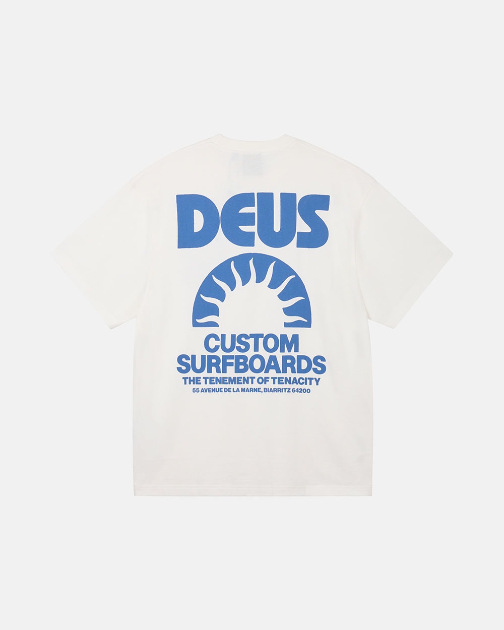 화이트 박시 반팔 티셔츠. 왼쪽 가슴에 블루 반원 태양과 'DEUS CUSTOMS' 소형 로고, 뒷면에는 'DEUS' 레터링과 태양 그래픽 아래 'CUSTOM SURFBOARDS' 문구가 큼직하게 프린트