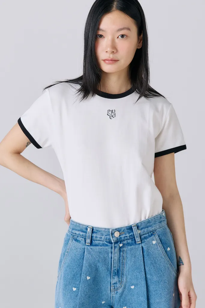 송지효가 검정 배색 링거 넥의 흰 반팔 티셔츠를 입고 있다.