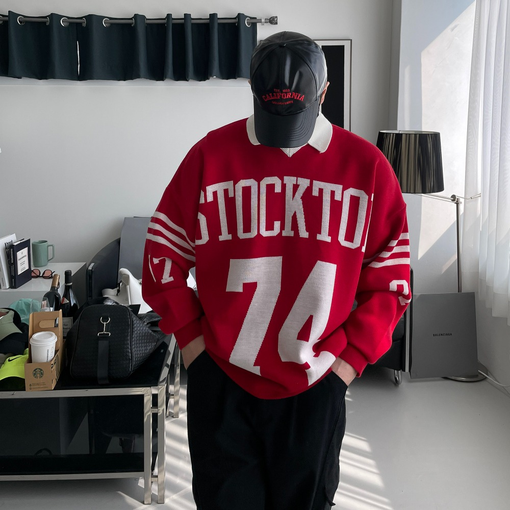 패딩 조끼 안에 입은 레드 럭비 니트. 화이트 칼라, 앞판 'STOCKTON 74' 레터링과 소매 스트라이프