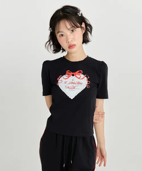스튜디오 토크 장면에서 입은 블랙 반팔 티셔츠. 퍼프 소매에 가슴 한가운데 레드 리본이 달린 하트 레이스 프린트와 필기체 문구가 들어간다