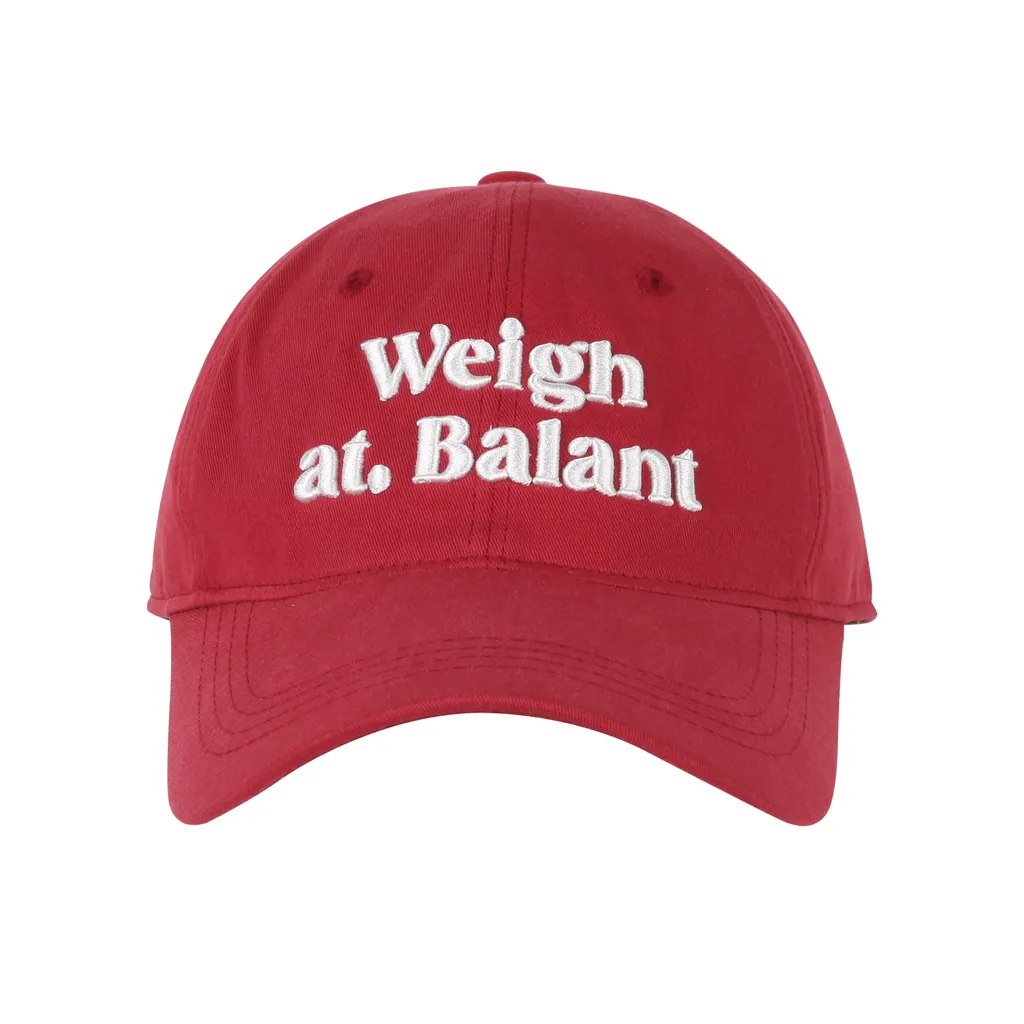 브릭 레드 코튼 6패널 볼캡. 앞면 중앙에 흰색 입체 자수 'Weigh at. Balant' 2줄 레터링, 굽은 챙.