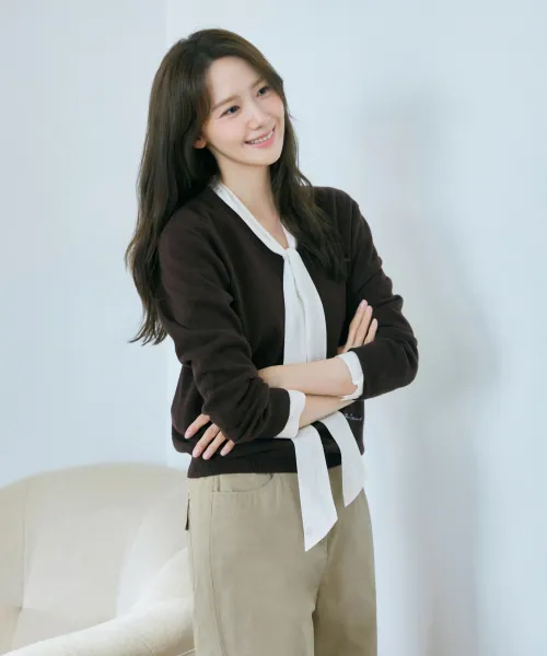 딥 브라운 컬러의 긴소매 브이넥 풀오버. 목선이 깊게 파여 안에 입은 블라우스의 타이가 드러나는 기본 실루엣