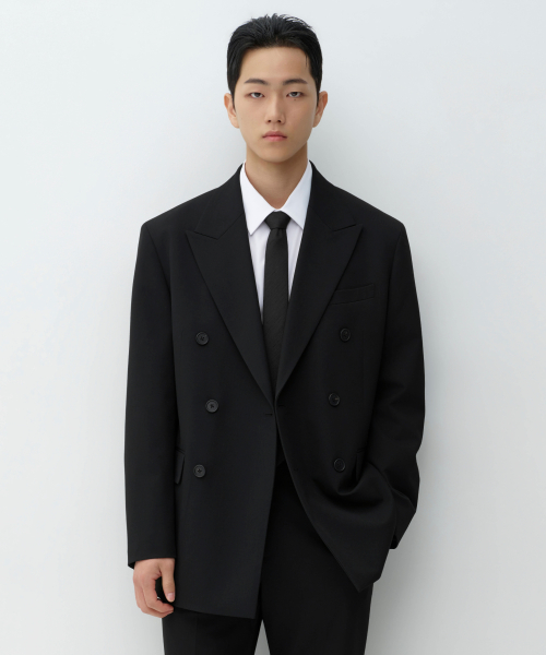 피크 라펄에 세 개씩 두 줄, 모두 여섯 개의 톤온톤 블랙 버튼이 달린 더블 브레스티드 재킷. 어깨선이 팔 쪽으로 내려앉은 오버사이즈 실루엣이고 왼쪽 가슴에 웰트 포켓, 허리 아래 양옆에 플랩 포켓이 있다