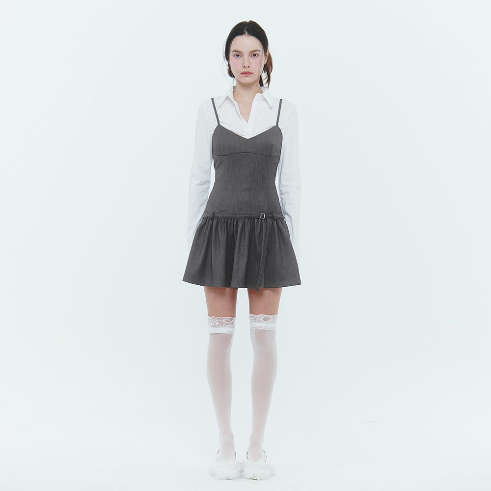 아이보리 스카프 셔츠 위에 레이어드한 미니 원피스. 멜란지 브라운(차콜에 가까운 톤) 원단, 가는 어깨끈의 캐미솔 상의, 허리선의 작은 버클 스트랩, 허리 아래 개더가 잡힌 드롭 웨이스트 플레어 스커트