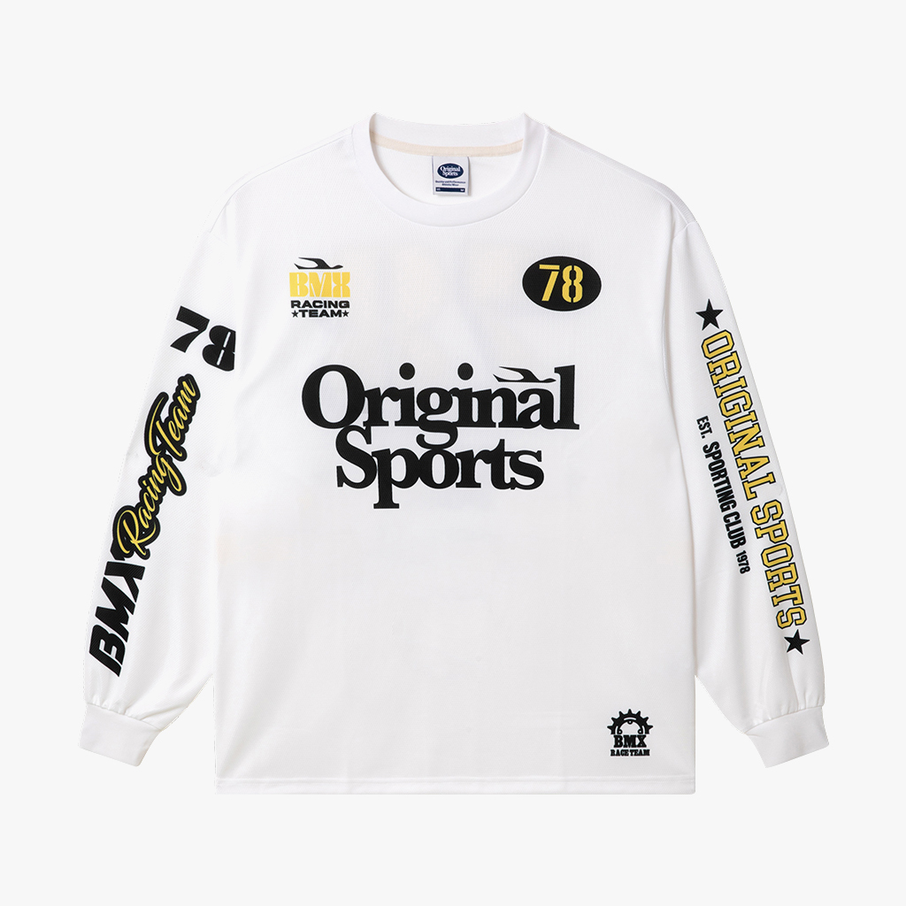 사무실 장면에서 입은 오프화이트 메쉬 롱슬리브 레이싱 저지. 가슴 블랙 Original Sports 레터링과 옐로 78 원형 그래픽, 양소매 블랙·옐로 레이싱 레터링
