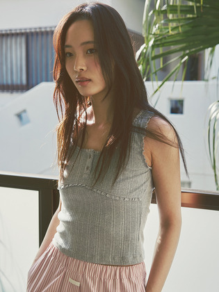 시장에서 장을 보는 장면에서 셔츠 안에 겹쳐 입은 멜란지 그레이 슬리브리스. 넥라인·암홀·가슴선을 따라 짧은 레이스가 둘러진 코튼 소재